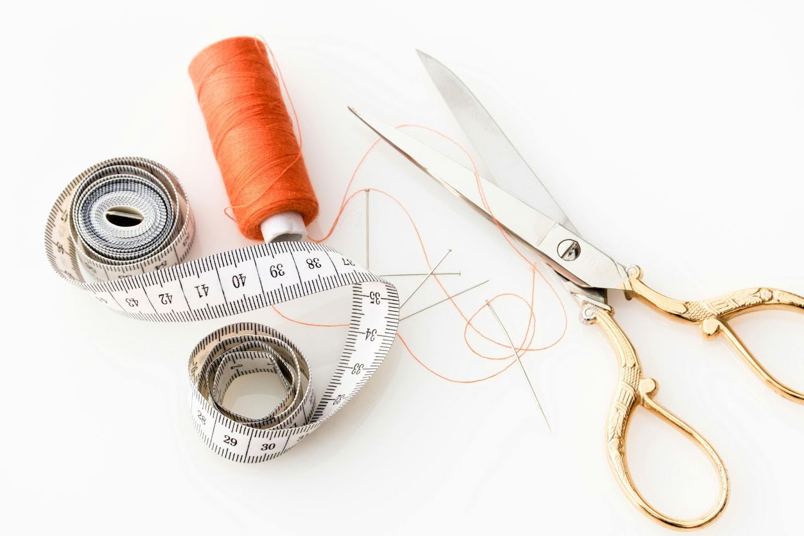 Scissors, tape measure and thread against a white background.